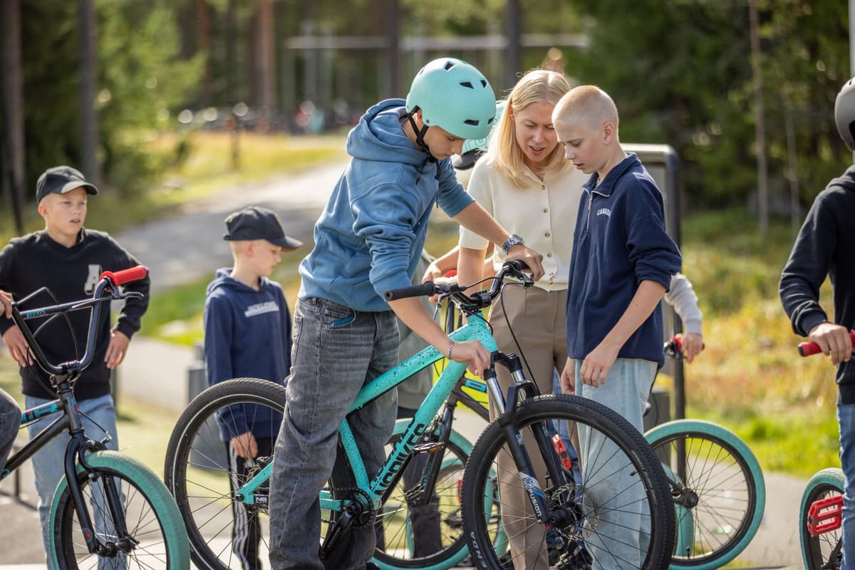 Högstadieelever på cyklar på en skolgård. De har hjälmar på huvudena.
