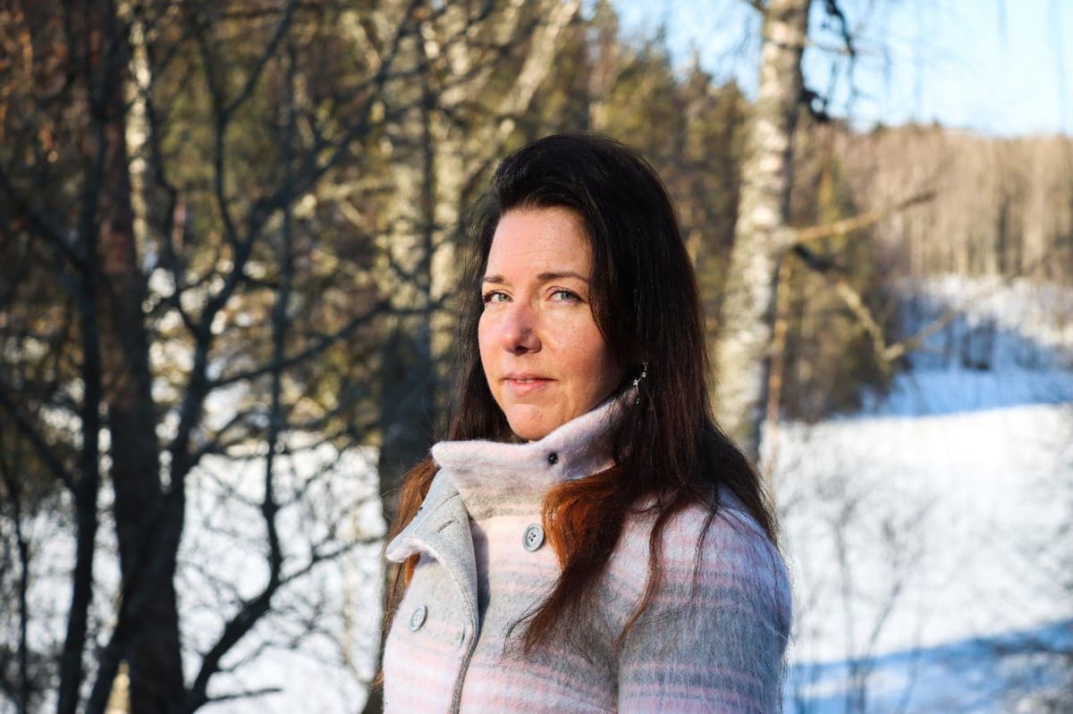 En kvinna som står i ett vintrigt naturlandskap.