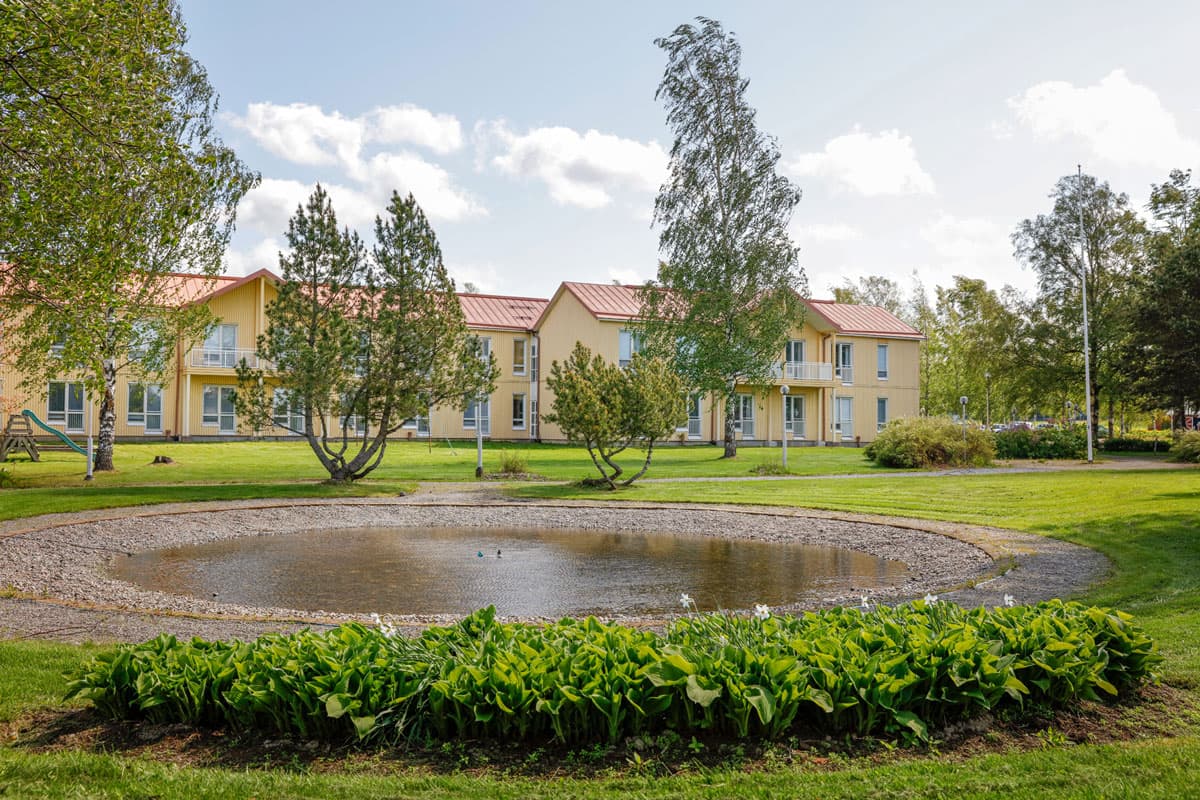 Ett gult stort villakomplex i parkmiljö.