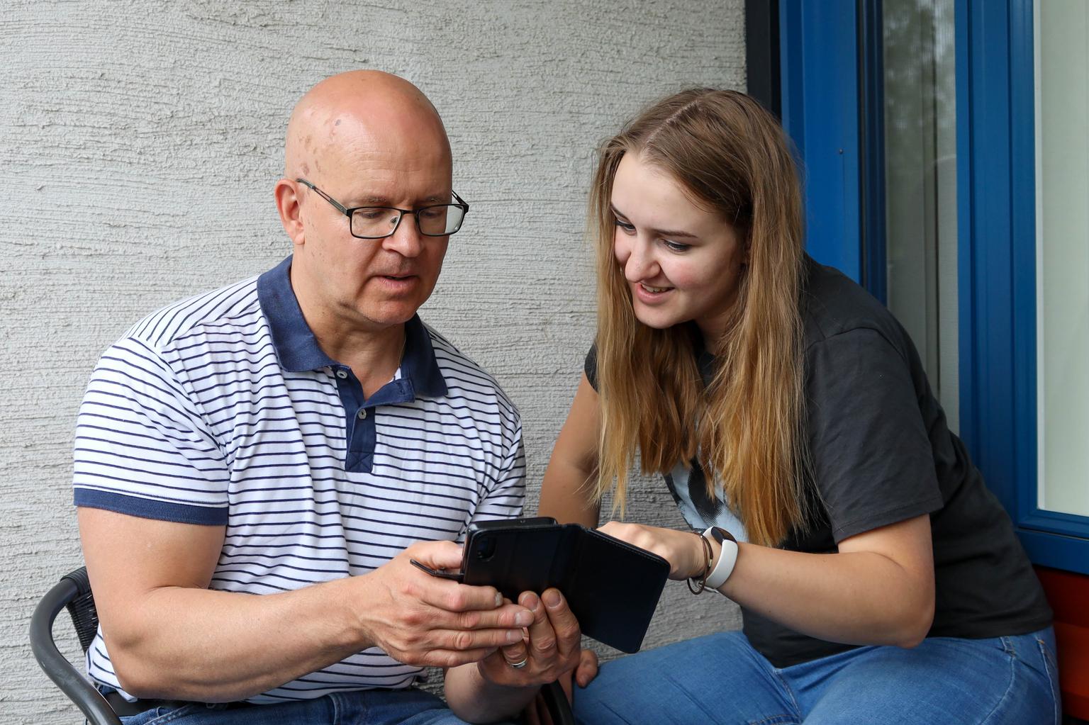En ung kvinna guidar en äldre man genom användning av digitala verktyg