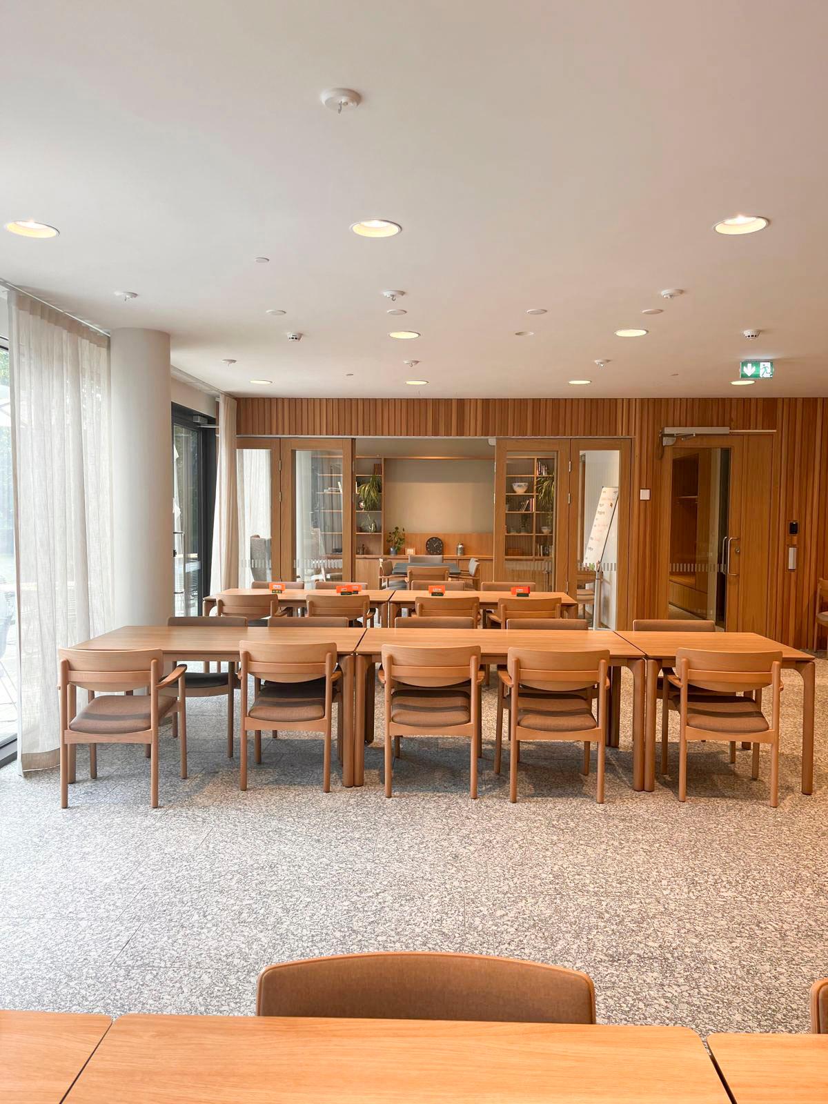 Restauranglokal med träinredning, bord och stolar samt serveringsdisk.