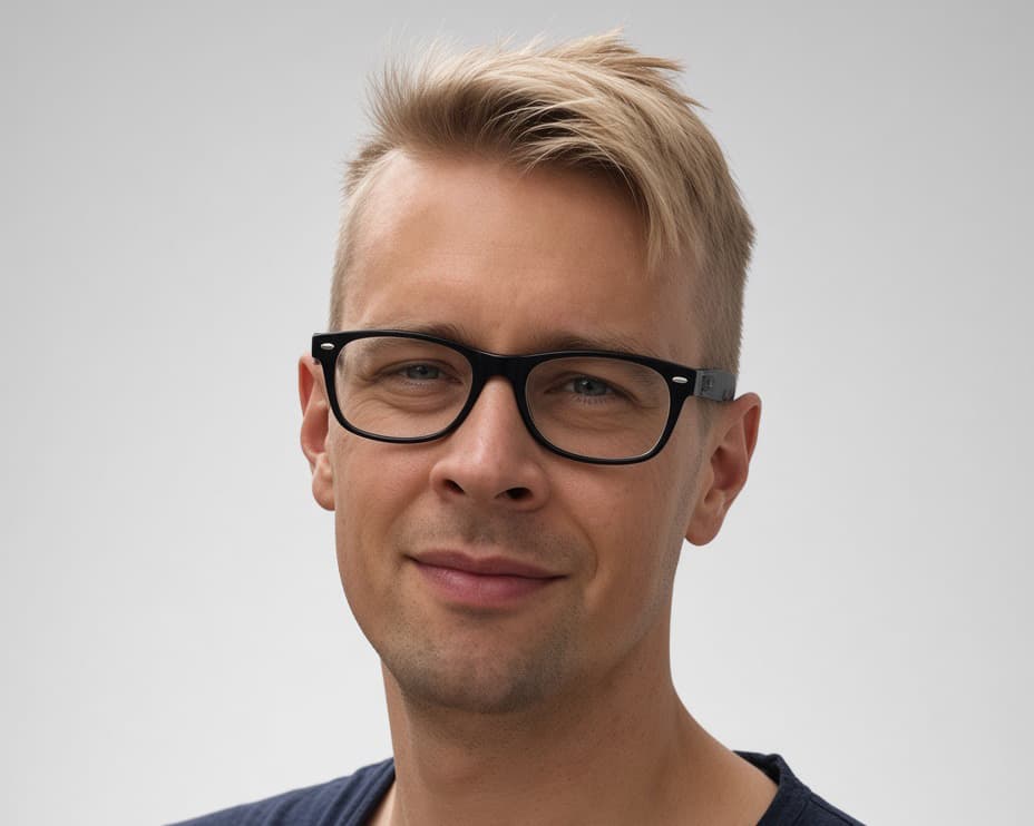 A portrait photo shows a blond man with black glasses against a light grey background. He is facing the camera with a slight smile.