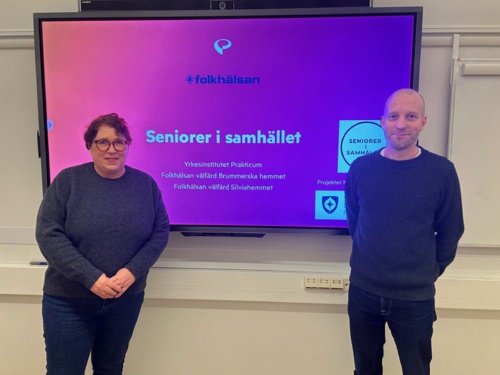 Brummerska hemmets enhetschef Christel Harjanne och Silviahemmets enhetschef Fredrick L&ouml;v-St&aring;hlberg, framf&ouml;r en stor bildsk&auml;rm.