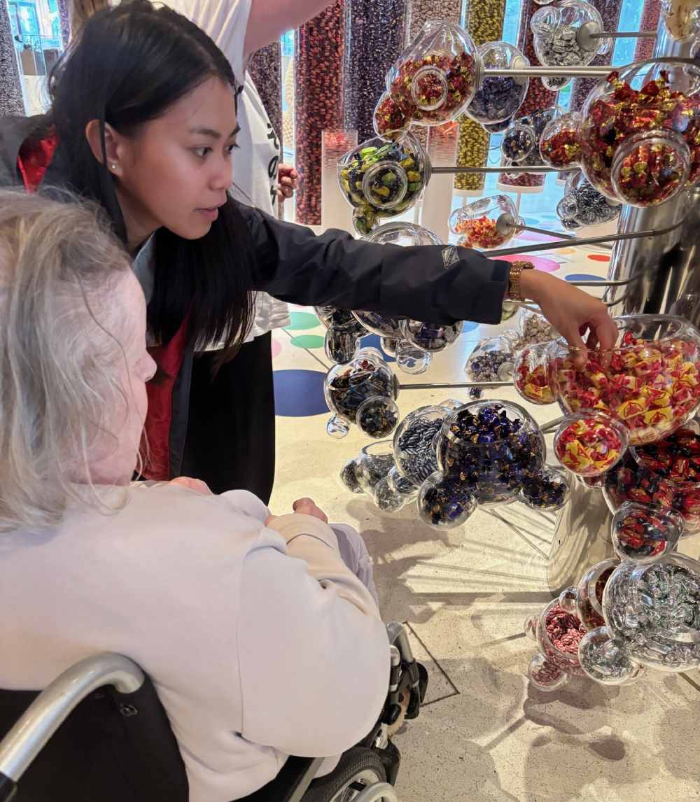 En v&aring;rdare bekantar sig med utbudet av karameller, tillsammans med en &auml;ldre person i Fazers bes&ouml;kcenter.