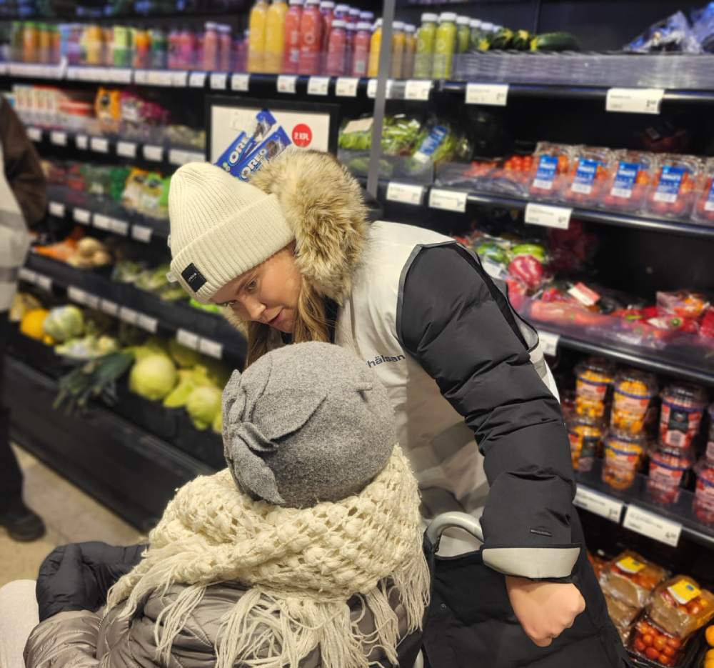 En äldre person i rullstol i en matbutik tillsammans med sin vårdare.