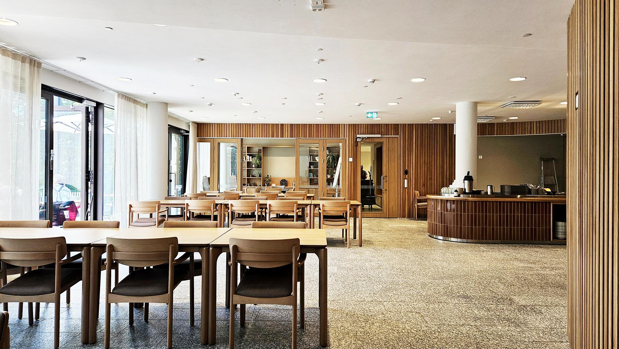 Ljus restaurang med tr&auml;bord, stolar och serveringsdisk p&aring; Folkh&auml;lsanhuset i Haga.