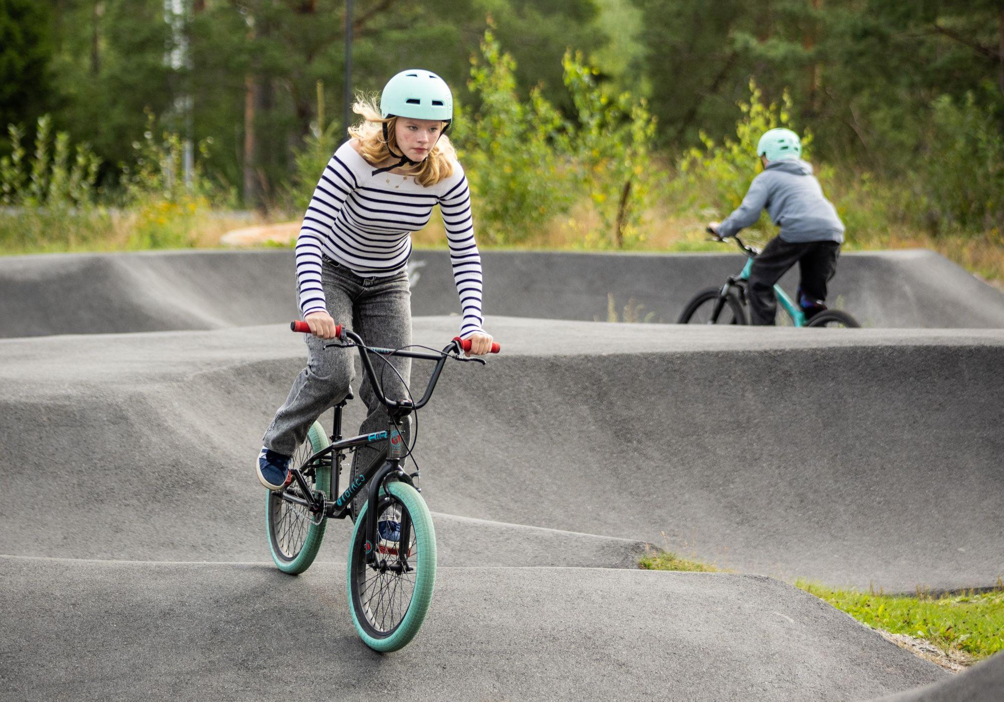 Tonårig flicka cyklar på en cykel i en pumptrack